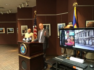 Top Flight Media's Darren Smith at Friday's press conference in city hall. At right, a rendering of a campaign poster at a city bus stop.