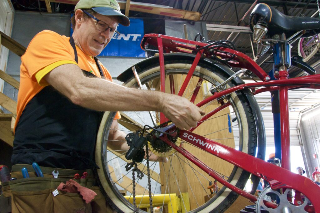 A Recycle Bicycle volunteer changes a chain, greg